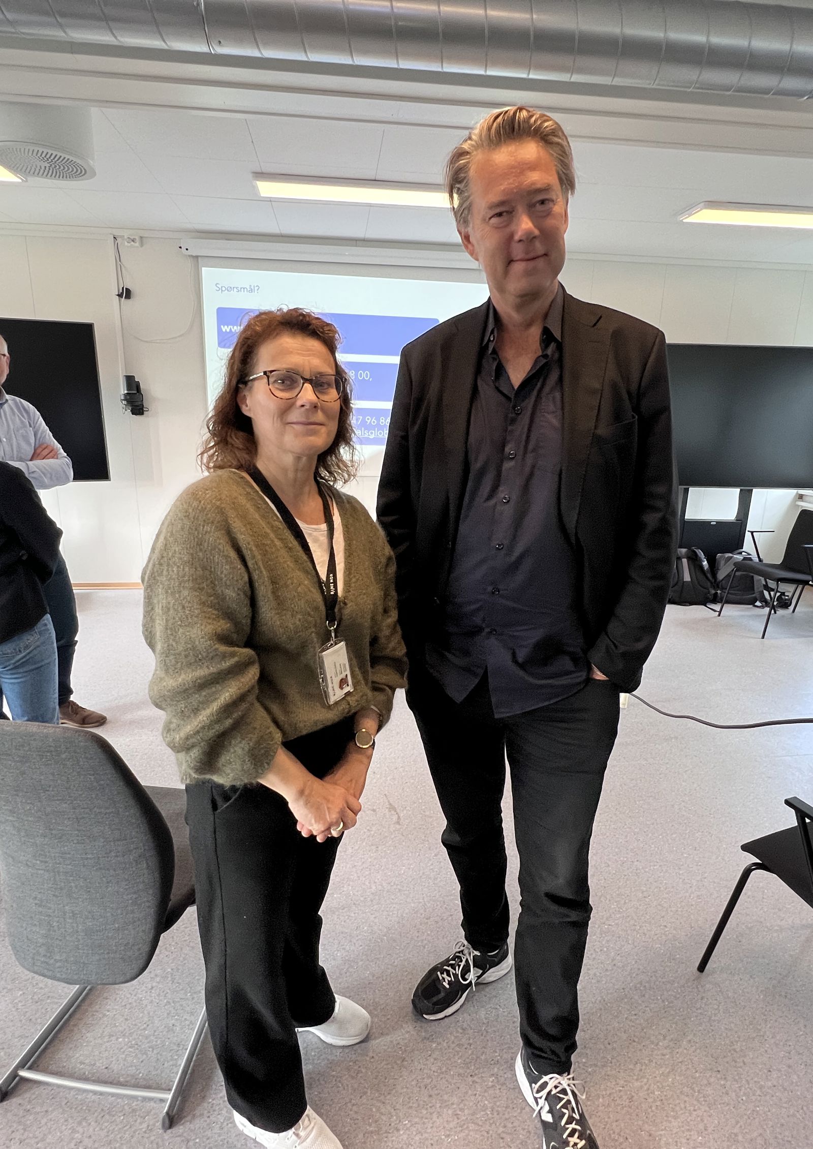 Kvinne og mann poserer i møterom