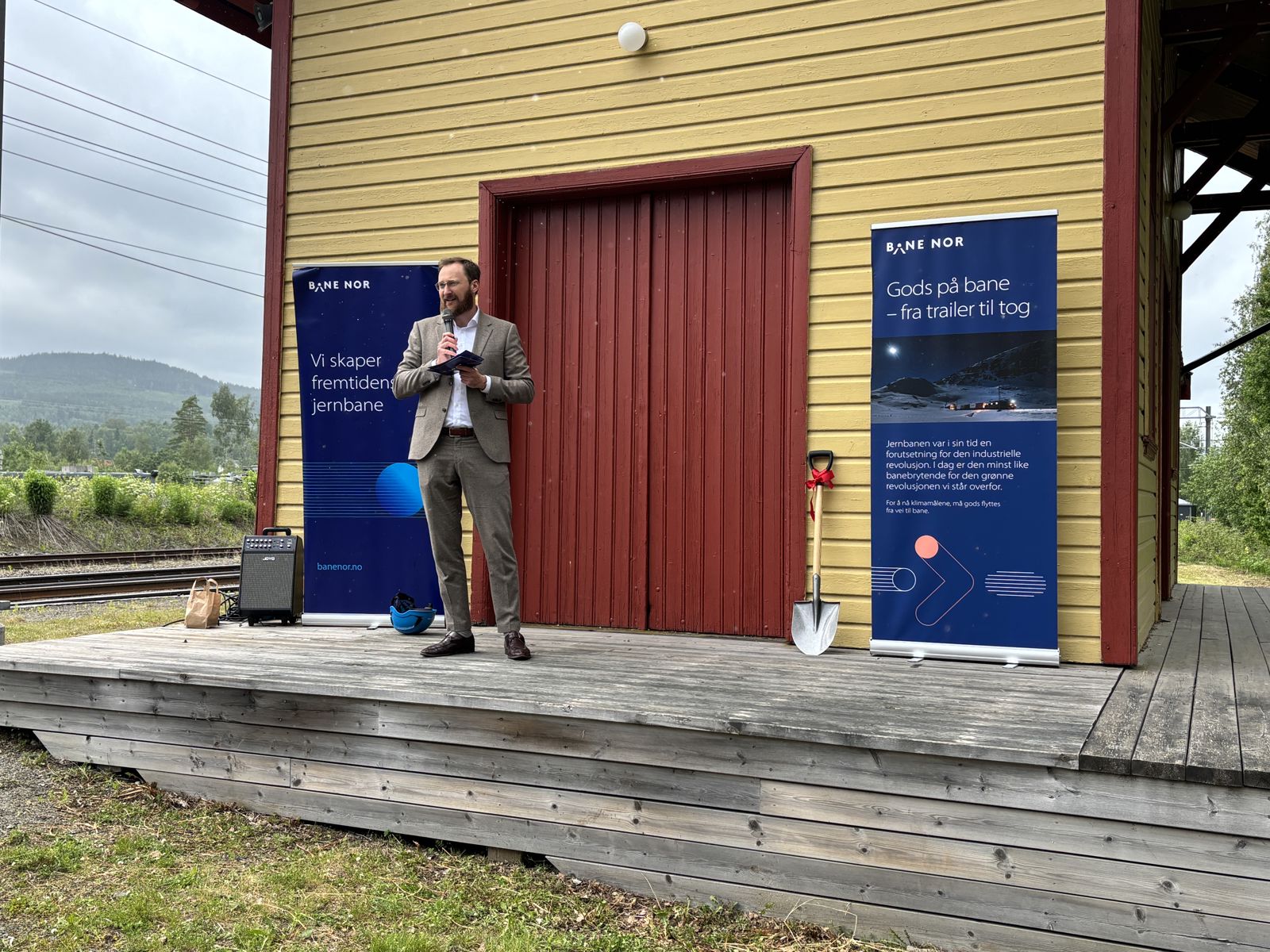 Mann står med mikrofon og taler. 