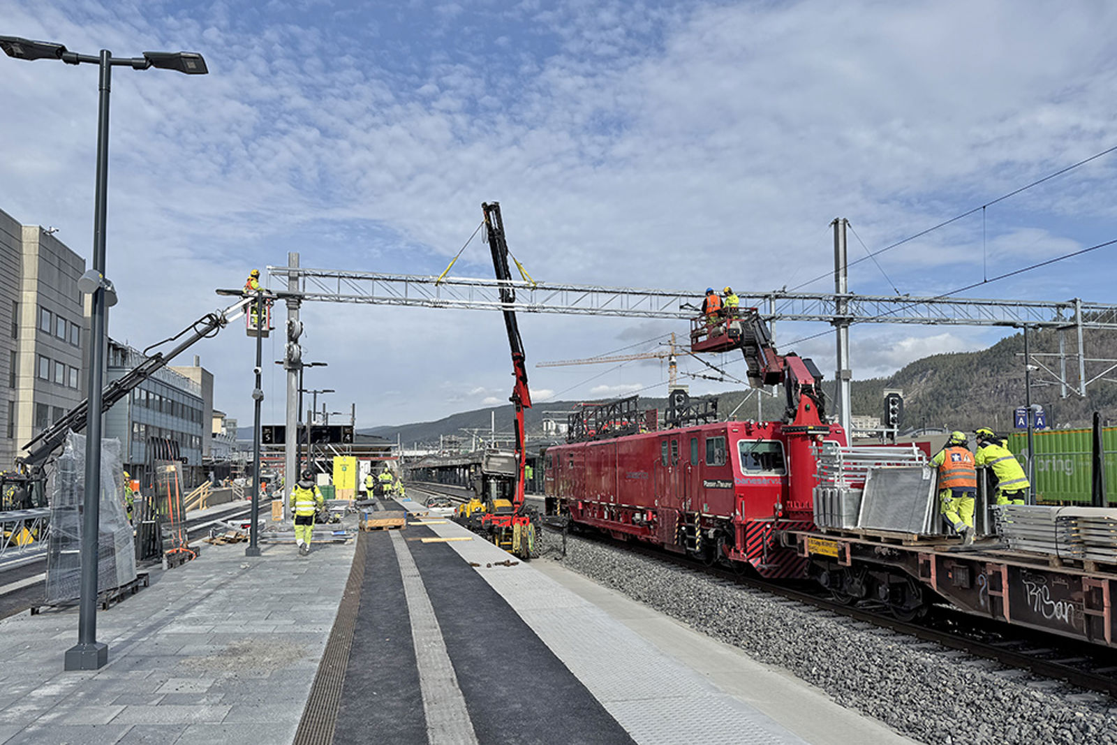 Skinnegående kran, flere lifter og mannskap i arbeid med montering av åk.
