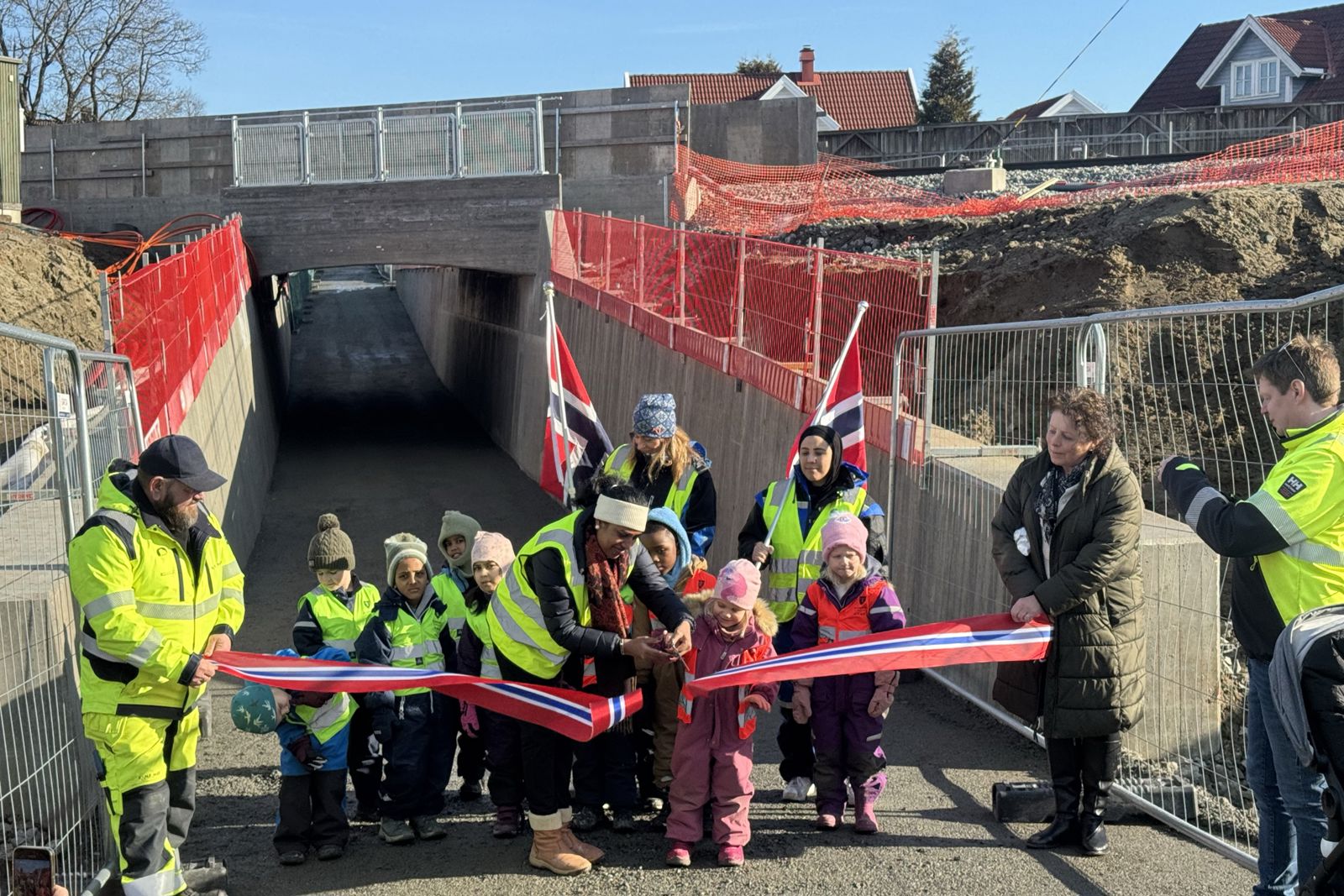 Foran undergangen holder to voksne snora, mens en gruppe barn klipper.