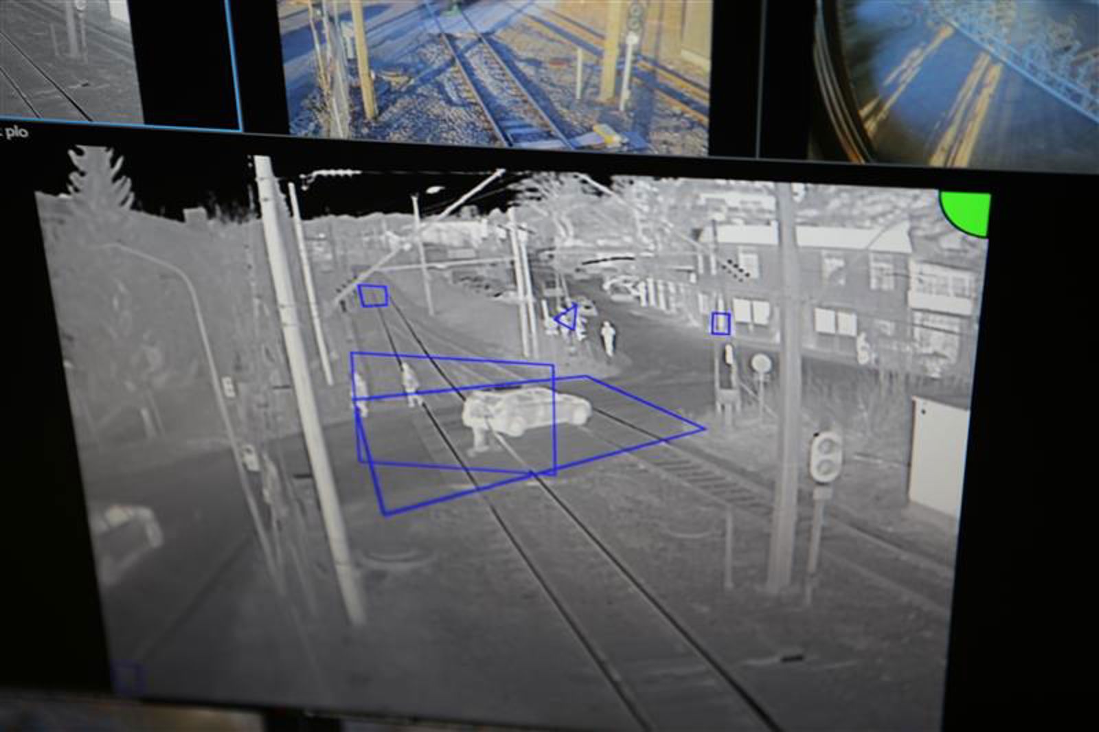 Kamera fanger opp at en bil står fanget mellom bommene på en planovergang, som ligger nede.