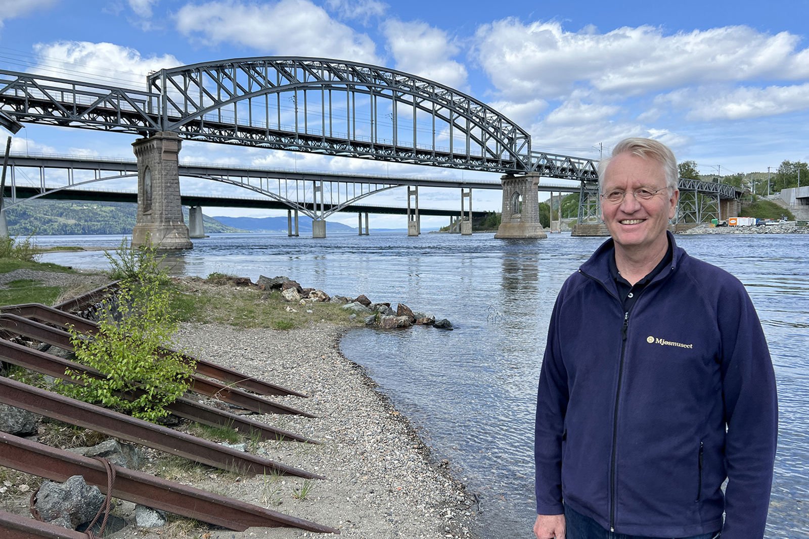 Personen står på stranda med elva Vorma og de tre bruene bak seg.