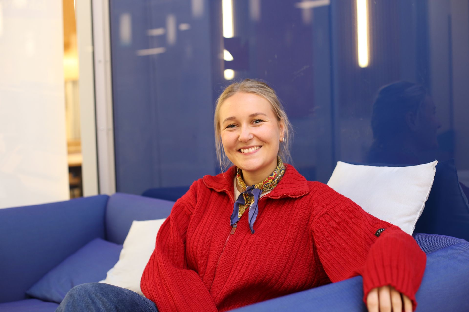 Trine Børseth, som studerer til togleder, sitter smilende i en sofa og ser mot kamera.